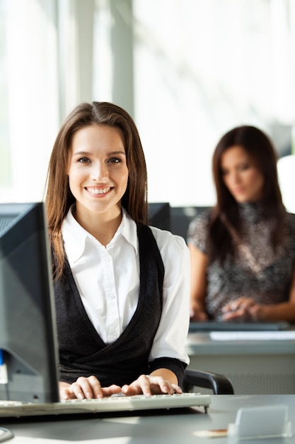 Retrato de mujer de negocios muy sonriente joven sentado en el lugar de trabajo