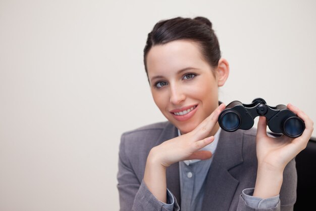 Retrato de mujer de negocios con prismáticos sonriendo