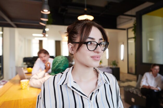 retrato de una mujer de negocios con ropa informal y gafas en el moderno interior de una oficina de planta abierta