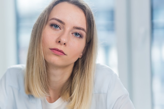 Retrato de una mujer de negocios rubia adulta joven mirando a la cámara en el interior de la oficina