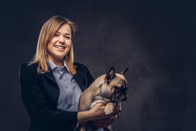 Retrato de una mujer de negocios rubia con traje formal sostiene un lindo perro