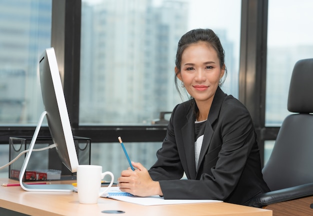 Retrato de mujer de negocios senior asiático sentado en su escritorio trabajando con la computadora en la oficina