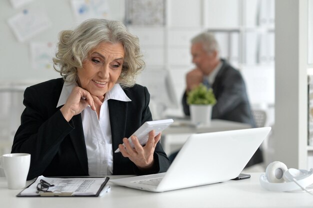 Retrato de mujer de negocios senior con portátil en la oficina