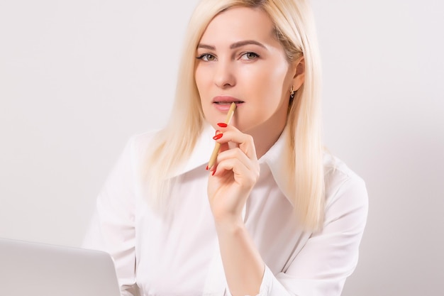 Retrato de una mujer de negocios seria que usa una computadora portátil en la oficina contra una pared blanca