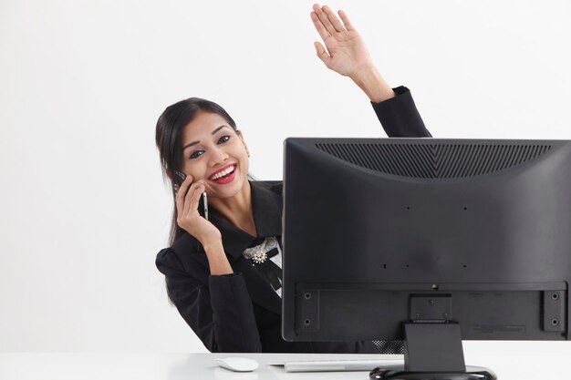 Retrato de una mujer de negocios sonriente hablando por teléfono móvil mientras hace gestos en la oficina