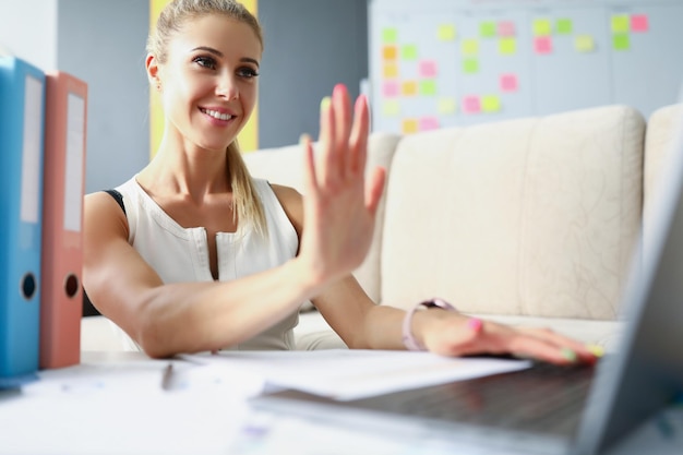 Retrato de mujer de negocios sonriente mirando portátil con alegría y felicidad mujer saludando