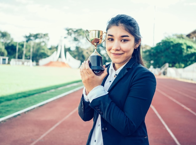 Foto retrato de una mujer de negocios sosteniendo un trofeo en la ciudad