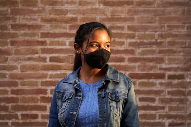 Retrato de una mujer negra afroamericana con mascarilla al aire libre.