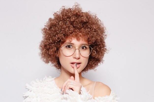 Retrato de mujer negra joven sonriente. Retrato de una bella mujer joven con corte de pelo afro afroamericano y maquillaje glamour. Tiro del estudio. Chica atractiva con anteojos.