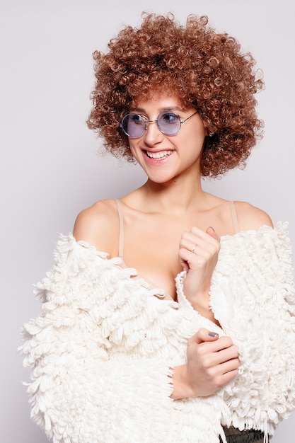 Retrato de mujer negra joven sonriente. Retrato de una bella mujer joven con corte de pelo afro afroamericano y maquillaje glamour. Tiro del estudio. Chica atractiva con anteojos