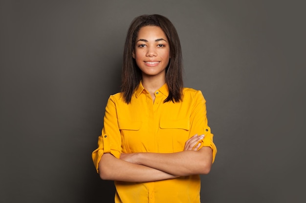 Retrato de una mujer negra sonriente con camisa amarilla