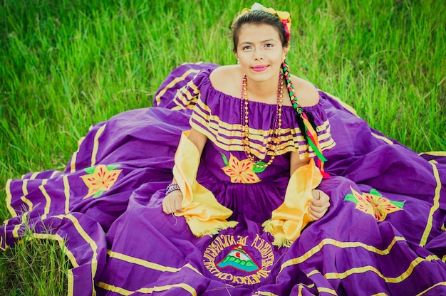 Retrato de mujer nicaragüense en traje folclórico sentado en el césped Joven mujer nicaragüense en traje folclórico tradicional sentado en el césped en el campo