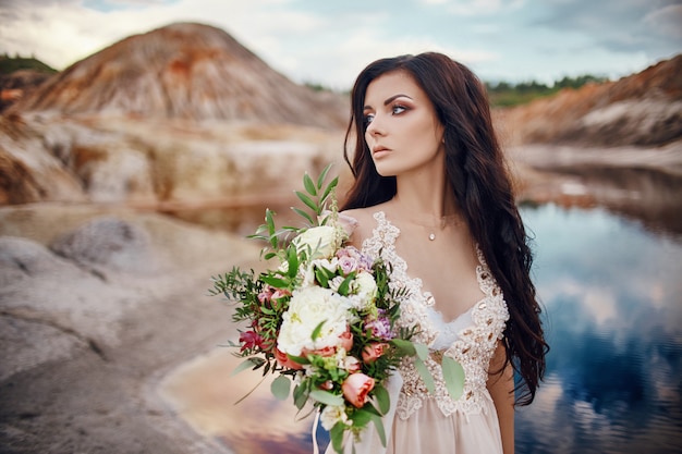 Retrato de mujer con ojos azules y ramo de flores en sus manos en la naturaleza.