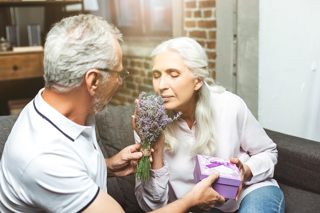 Foto retrato de mujer oliendo ramo de lavanda en manos de hombres en casa