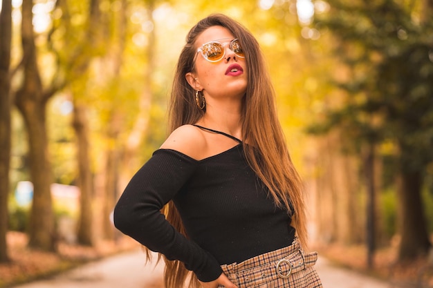 Retrato de una mujer en otoño en un bosque con hojas marrones al atardecer en un parque de la ciudad