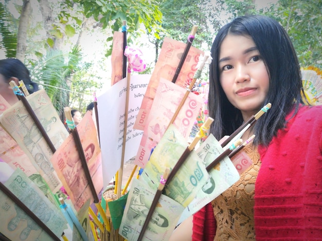 Foto retrato de una mujer con papel moneda de pie contra un árbol