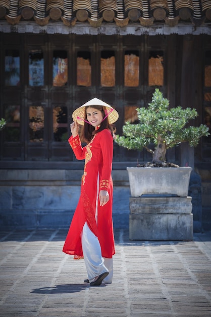 Foto retrato de una mujer con un paraguas rojo de pie contra una estructura construida