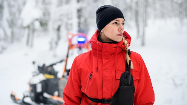 Retrato de mujer paramédico del servicio de rescate de montaña al aire libre en invierno en el bosque