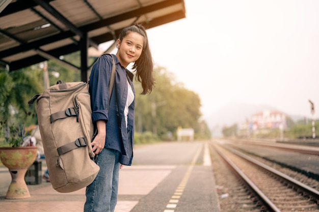 Retrato de mujer pasajera con mochila en la plataforma del ferrocarril esperando el viaje en tren.Concepto de turismo, viajes y recreación.