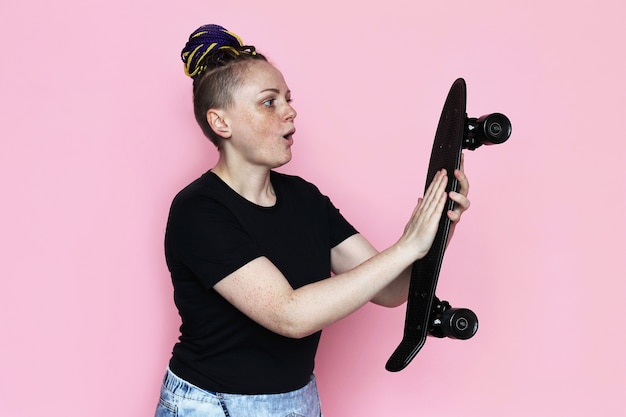 Retrato de mujer con patineta en sus manos y mirándolo.