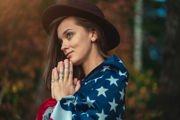 Retrato de mujer patriótica indie atractiva con sombrero con bandera americana con anillos de plata con piedra turquesa al aire libre. Viaja a América y celebra la fiesta del 4 de julio en estados unidos