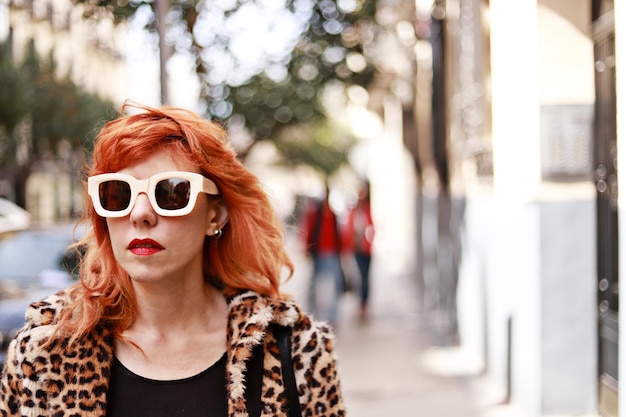 Retrato de mujer pelirroja con gafas de sol de moda en la calle con espacio para copiar