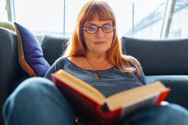 Foto retrato de una mujer pelirroja leyendo una novela