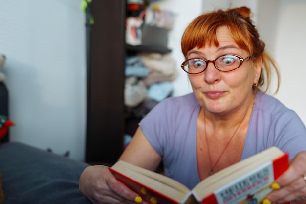 Foto retrato de una mujer pelirroja leyendo una novela