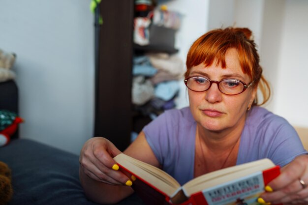 Foto retrato de una mujer pelirroja leyendo una novela