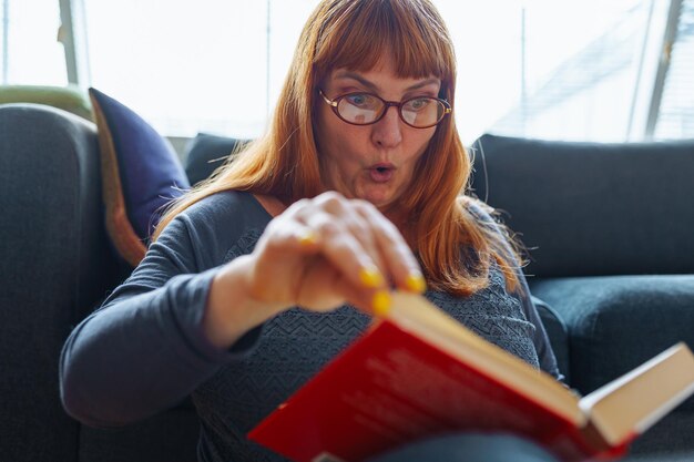 Retrato de una mujer pelirroja leyendo una novela