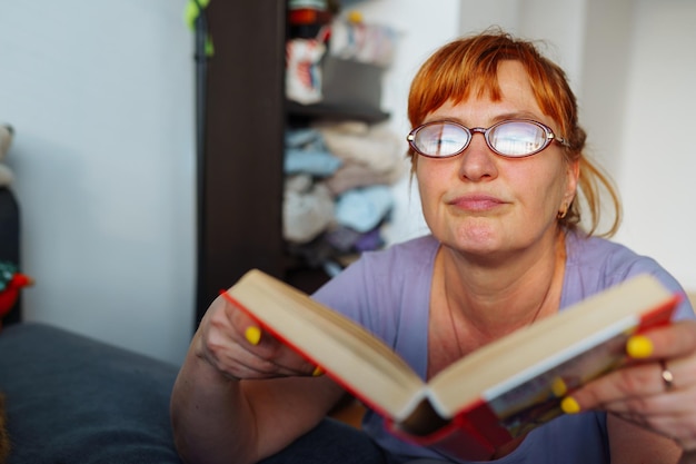 Foto retrato de una mujer pelirroja leyendo una novela