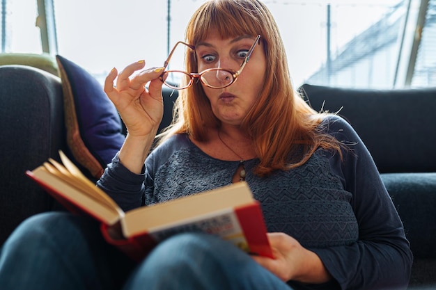 Foto retrato de una mujer pelirroja leyendo una novela