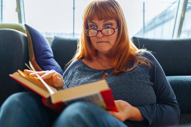 Foto retrato de una mujer pelirroja leyendo una novela