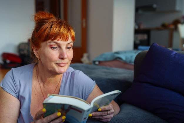 Foto retrato de una mujer pelirroja leyendo una novela