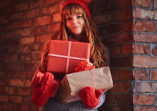 Retrato de mujer pelirroja con ropa de abrigo tiene regalo de Navidad.