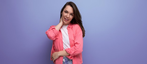 Retrato de una mujer de pelo negro bastante joven en una camisa rosa con una sonrisa de Hollywood en un estudio