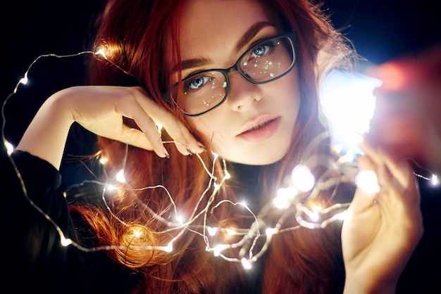 Foto retrato, de, mujer, con, pelo rojo, en, luces navideñas