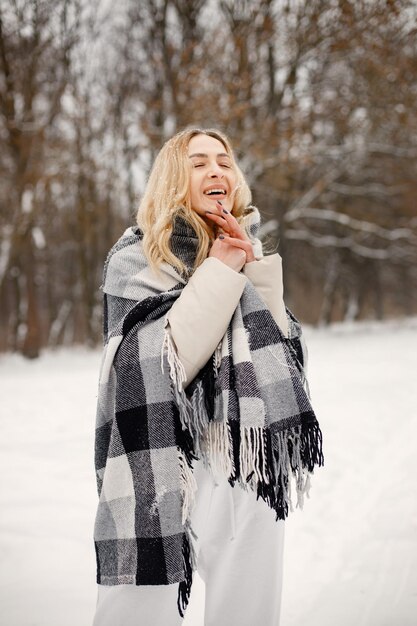 Retrato de una mujer de pie en el bosque de invierno y posando para una foto