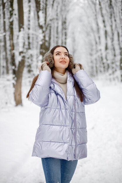 Retrato de una mujer de pie en el bosque de invierno y posando para una foto