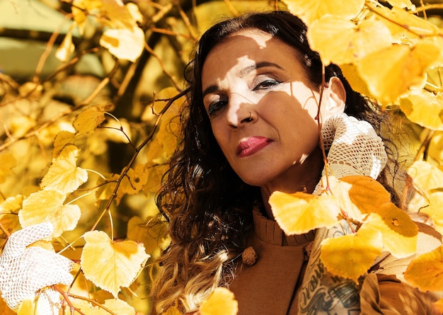 Foto retrato de una mujer de pie en medio de las hojas de otoño