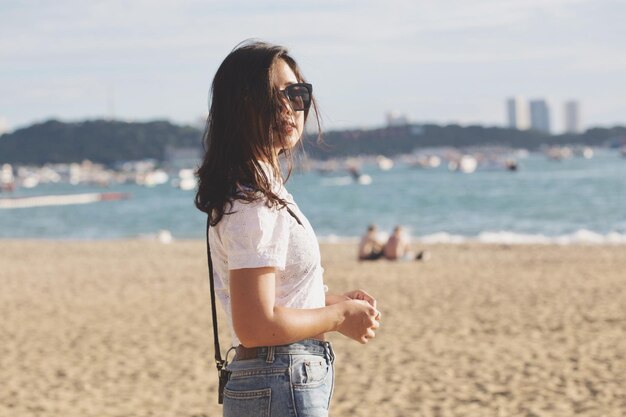 Foto retrato de una mujer de pie en la playa contra el mar y el cielo