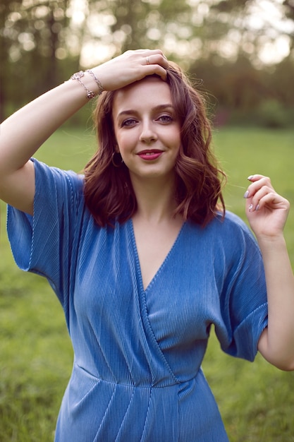 Retrato de una mujer de pie sobre un campo verde con un vestido azul