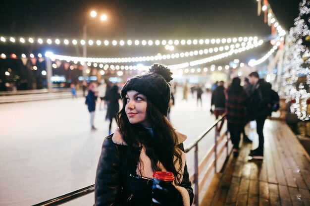 Retrato de mujer en la pista de patinaje sobre hielo de Navidad