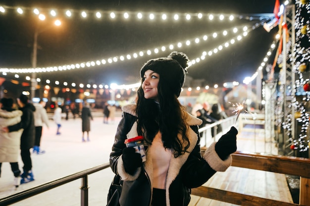 Retrato de mujer en la pista de patinaje sobre hielo de Navidad