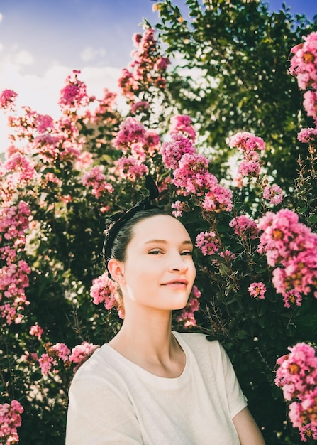 Retrato de una mujer con plantas de flores rosadas en un parque