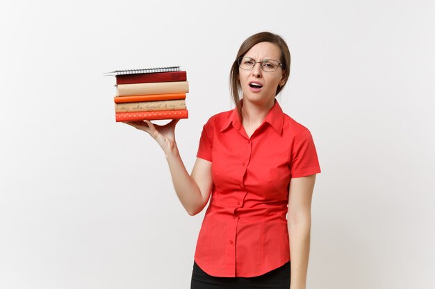 Retrato de mujer de profesor de negocios molesto frustrado cansado en gafas de camisa roja sosteniendo libros de texto de pila en manos aisladas sobre fondo blanco. Educación o enseñanza en el concepto de universidad de secundaria.