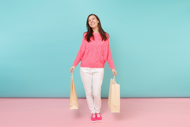 Retrato de mujer de punto rosa suéter pantalones blancos sosteniendo bolsas de paquetes multicolores con compras