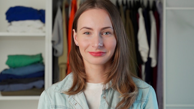 Retrato de una mujer que se encuentra en el contexto de un gran armario un armario con ropa elegante y artículos para el hogar.