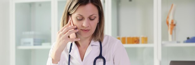 Retrato de una mujer que habla por teléfono en la mesa de la consulta médica de primer plano de la clínica