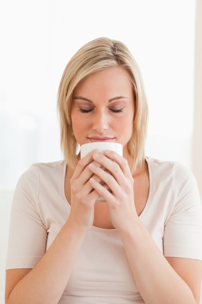 Retrato de una mujer que huele su taza de café